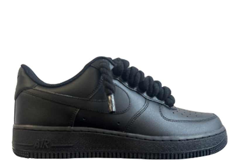 Schwarzer Nike Air Force 1 Sneaker mit schwarzen, dicken Rope-Schnürsenkeln, die dem klassischen Design des Schuhs einen auffälligen und modernen Akzent verleihen. Der Schuh hat eine matte Oberfläche und eine robuste schwarze Sohle, die für einen markanten Look sorgt.