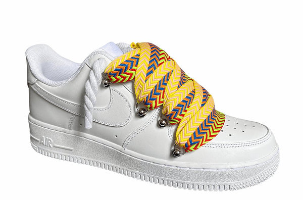 Weißer Nike Air Force 1 Sneaker mit Lanvin und Rope Seil-Schnürsenkeln in einem gelb-blau-roten Zickzack-Muster, "Lanvin" sowie Metallösen und einer robusten Sohle für einen modernen, auffälligen Look, von der Seite.