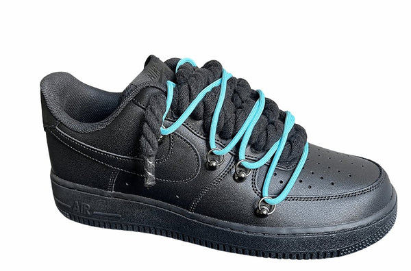 Schwarzer Nike Air Force 1 Sneaker mit dicken schwarzen Rope-Schnürsenkeln, kombiniert mit türkisfarbenen Akzent-Schnüren. Der Schuh hat eine matte schwarze Oberfläche, Metallösen und eine robuste Sohle, die dem Design einen modernen und markanten Look verleiht, von der Seite.