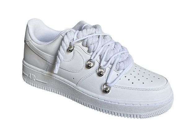 Weißer Nike Air Force 1 Sneaker mit dicken weißen Rope-Schnürsenkeln, kombiniert mit weißen Akzent-Schnüren. Der Schuh hat eine matte weiße Oberfläche, Metallösen und eine robuste Sohle, die dem Design einen modernen und markanten Look verleiht, von der Seite.