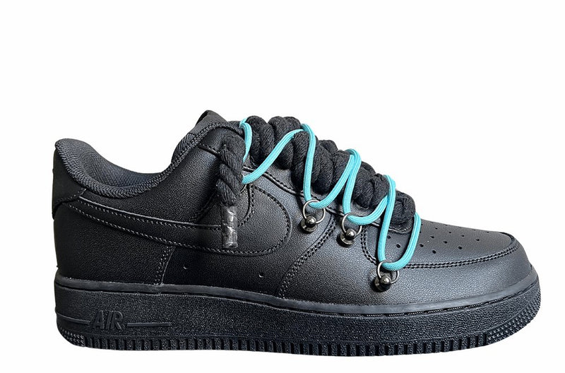 Schwarzer Nike Air Force 1 Sneaker mit dicken schwarzen Rope-Schnürsenkeln, kombiniert mit türkisfarbenen Akzent-Schnüren. Der Schuh hat eine matte schwarze Oberfläche, Metallösen und eine robuste Sohle, die dem Design einen modernen und markanten Look verleiht.